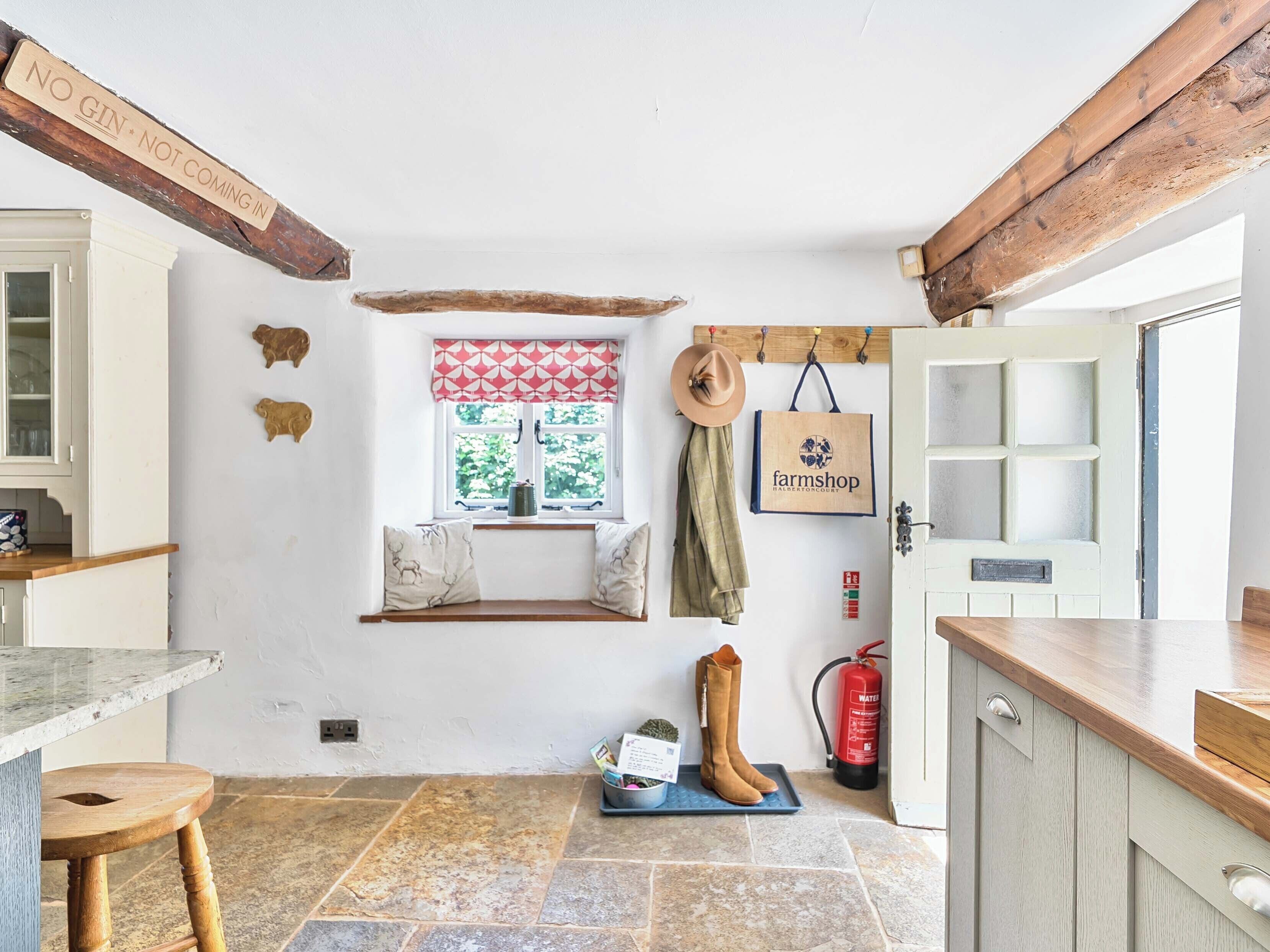 Una cocina rústica con piso de piedra, una ventana con cortina a cuadros rojos y blancos, un extintor y un letrero que dice 'farmshop'.