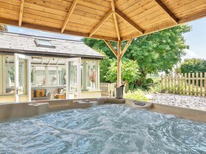 A hot tub under a wooden pergola with a view of a house and greenery. - 2 Pigsfoot Cottages (Tiverton)