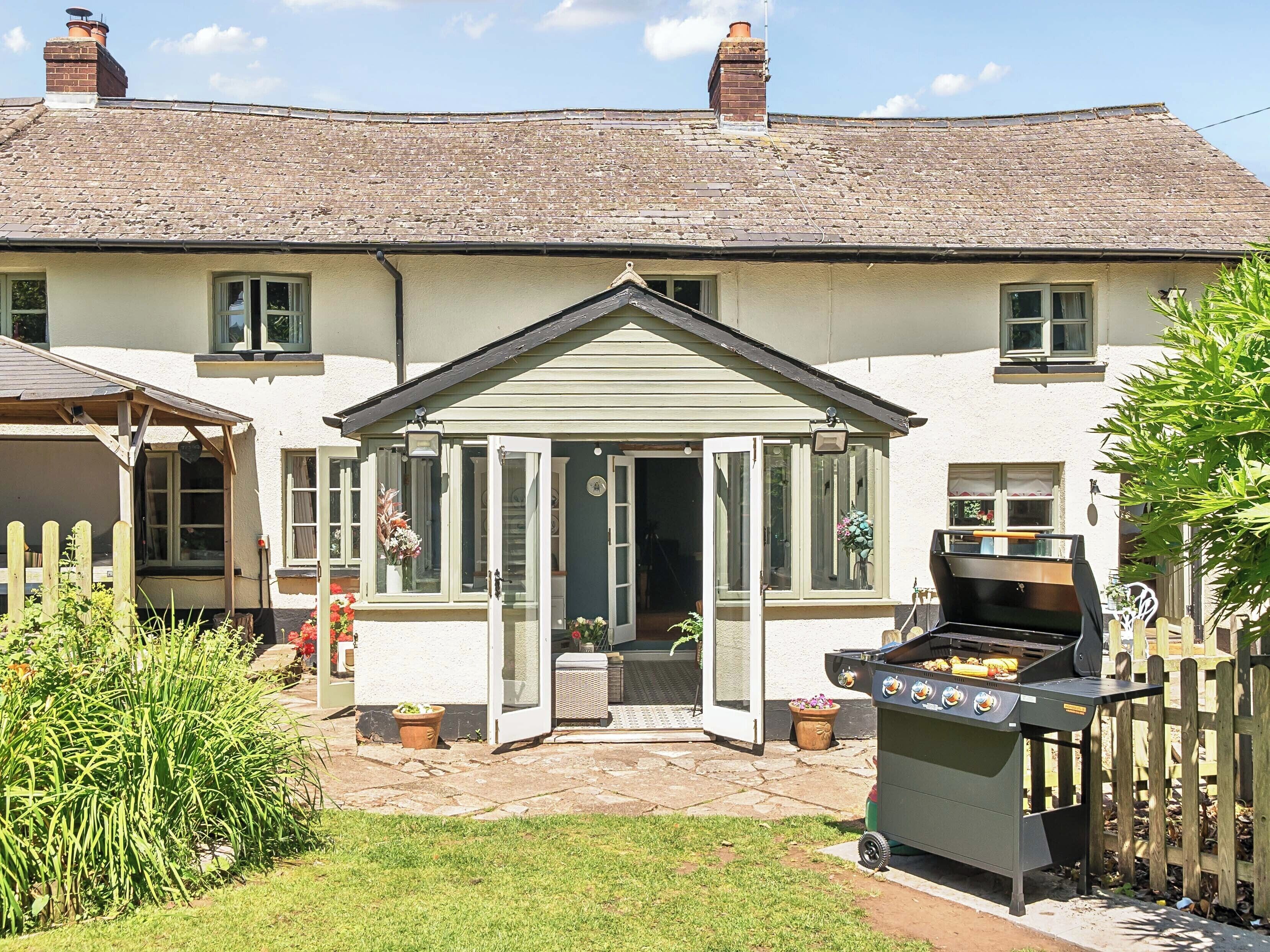A house with a covered patio, a barbecue grill, and a garden.