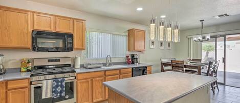A modern kitchen with wooden cabinets, a microwave, stove, and a dishwasher.