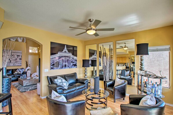 A modern living room with a ceiling fan, leather sofas, a glass coffee table, and artwork on the walls. - Luxury Glendale Getaway w/ Private Hot Tub & Patio (Glendale)