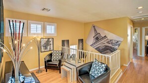 A spacious living area with a modern sofa, a coffee table, and a decorative plant. There are framed pictures on the walls and a large artwork depicting a famous landmark. - Luxury Glendale Getaway w/ Private Hot Tub & Patio (Glendale)