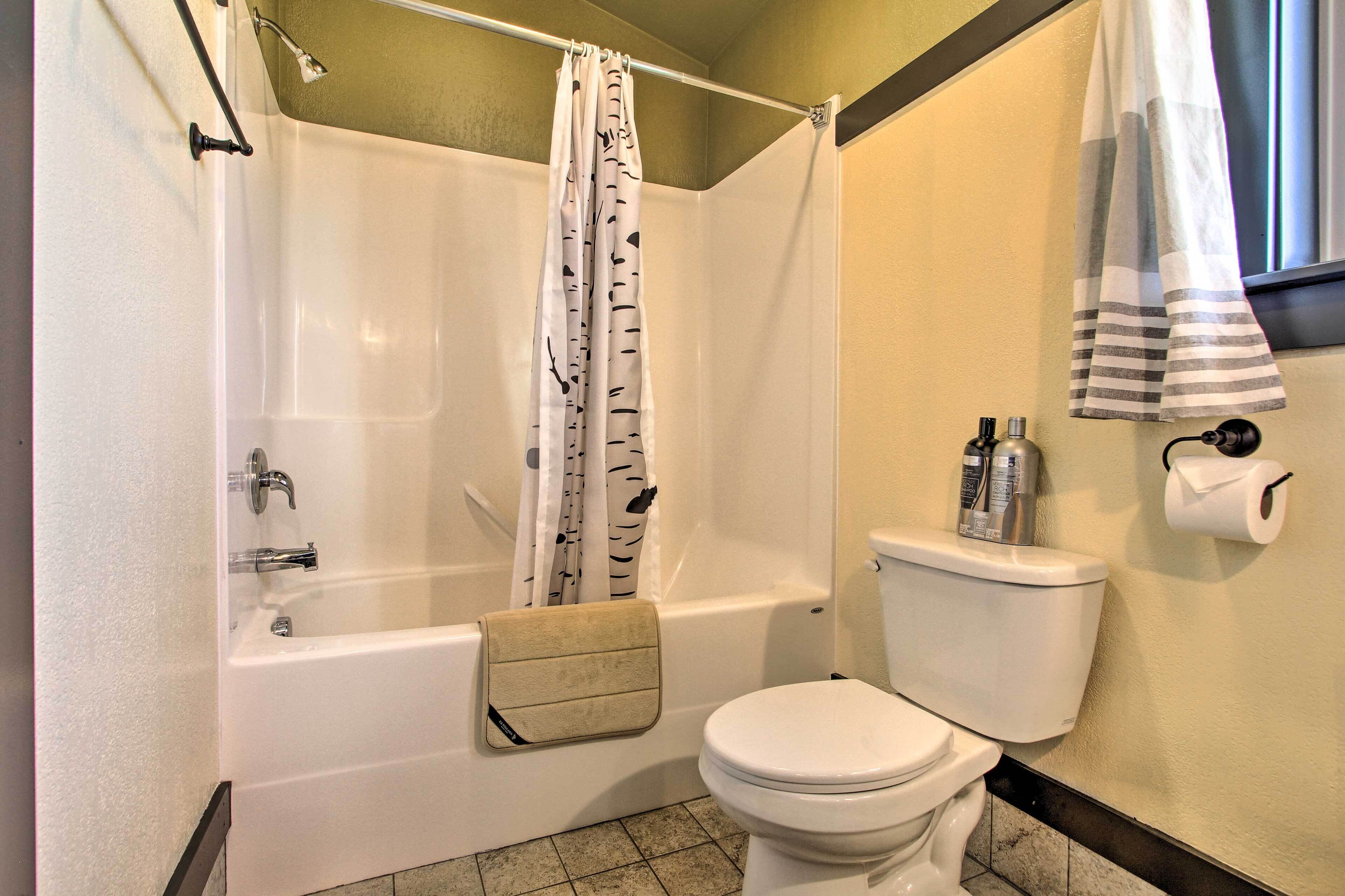 A bathroom with a bathtub, toilet, and shower curtain.