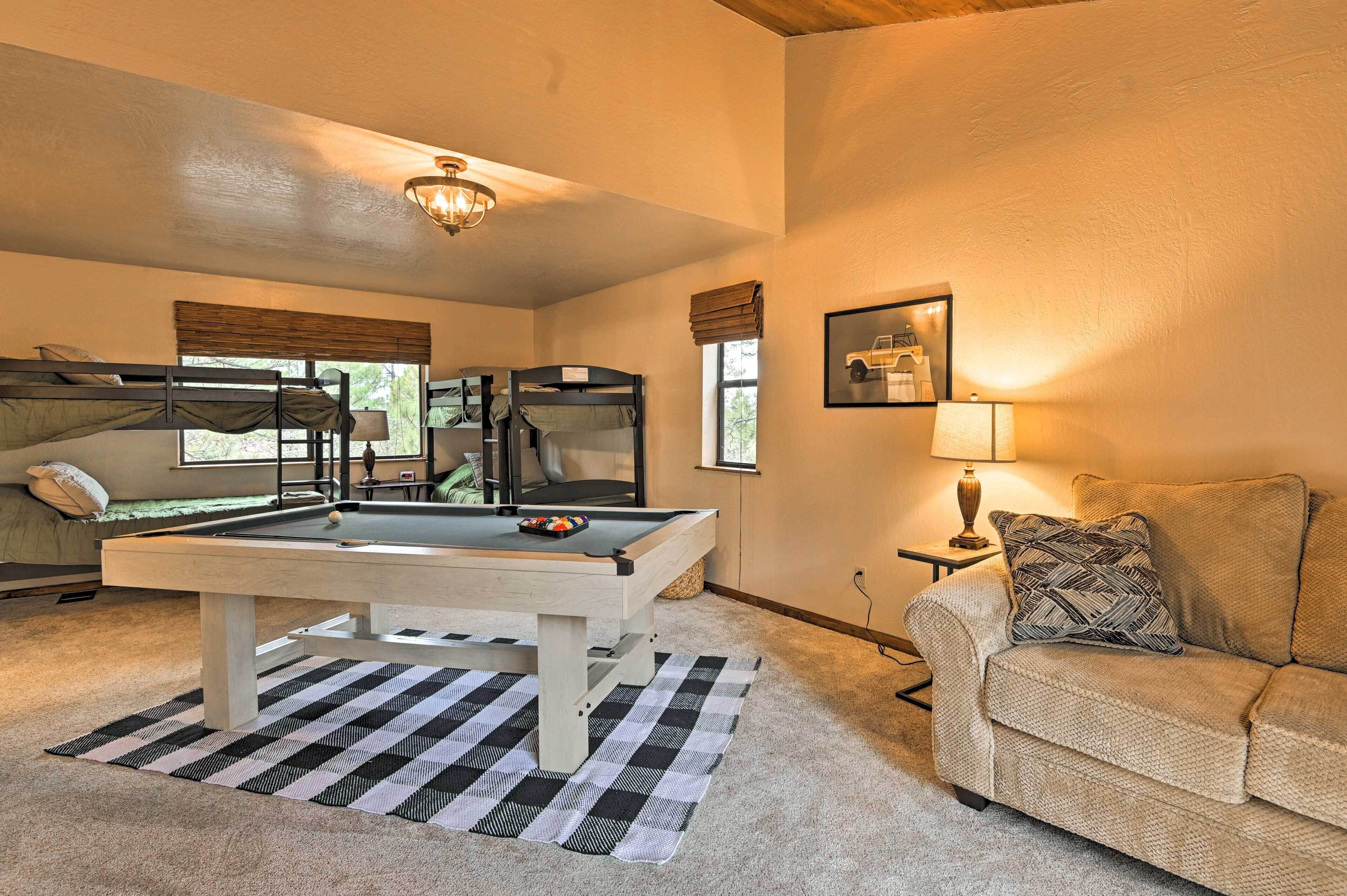 Une pièce confortable avec des lits superposés, une table de billard, un canapé et une lampe.