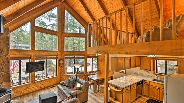 A spacious cabin with a high ceiling, large windows, a cozy living area with a fireplace, and a separate dining and kitchen area. - 1 Mi to Lake: Secluded Cabin w/ Deck in Munds Park (Munds Park)