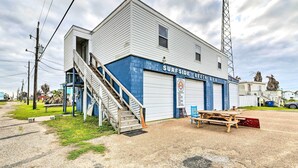 A building with a blue and white exterior, a staircase leading to the entrance, and a sign reading "SURFSIDE BEACH". - Relaxing Surfside Bunkhouse - Walk to the Beach! (Freeport)