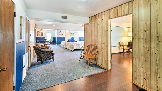 A room with a wooden floor, a large bed, a chair, and a desk. - Relaxing Surfside Bunkhouse - Walk to the Beach! (Freeport)