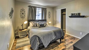 Quarto com cama, luminárias de cabeceira, tapete, armário e arte decorativa na parede.