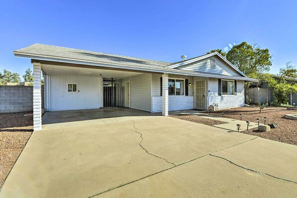 A single-story house with a covered garage, a front porch, and a small garden area with decorative lights.