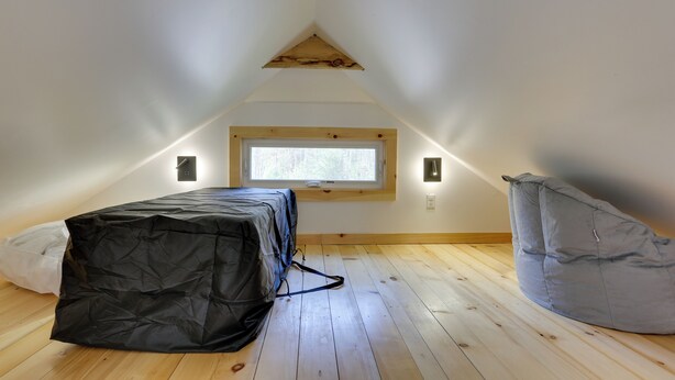 A small attic room with a sloped ceiling, a window, and a bean bag chair. - Cozy Catskills Tiny Home ~ 3 Mi to Bethel Woods! (Swan Lake)