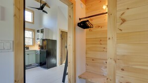 A modern kitchen with a stainless steel refrigerator, wooden cabinets, and a black hanging rack. - Cozy Catskills Tiny Home ~ 3 Mi to Bethel Woods! (Swan Lake)