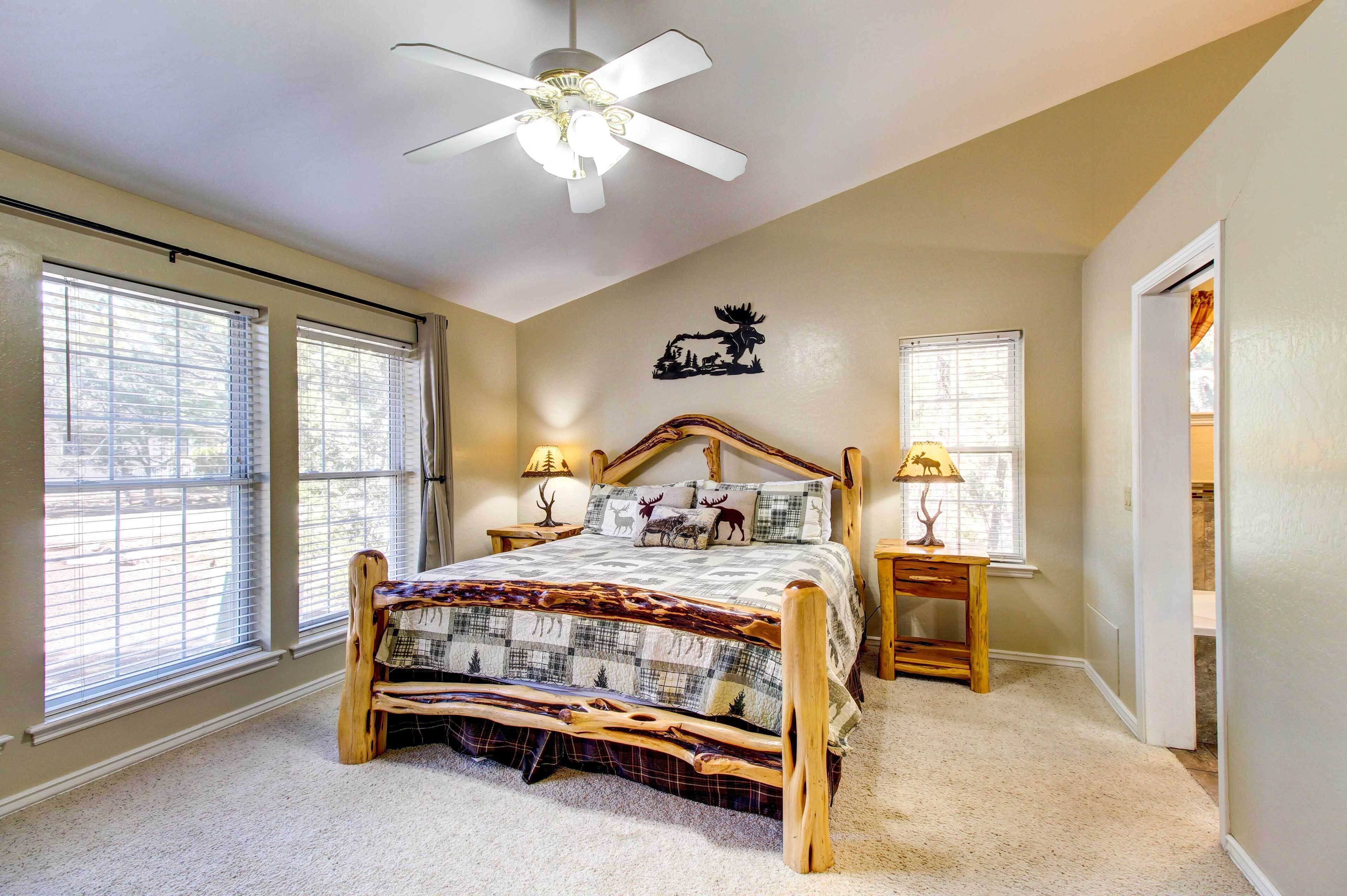 A bedroom with a wooden bed, two bedside lamps, a ceiling fan, and large windows with blinds.