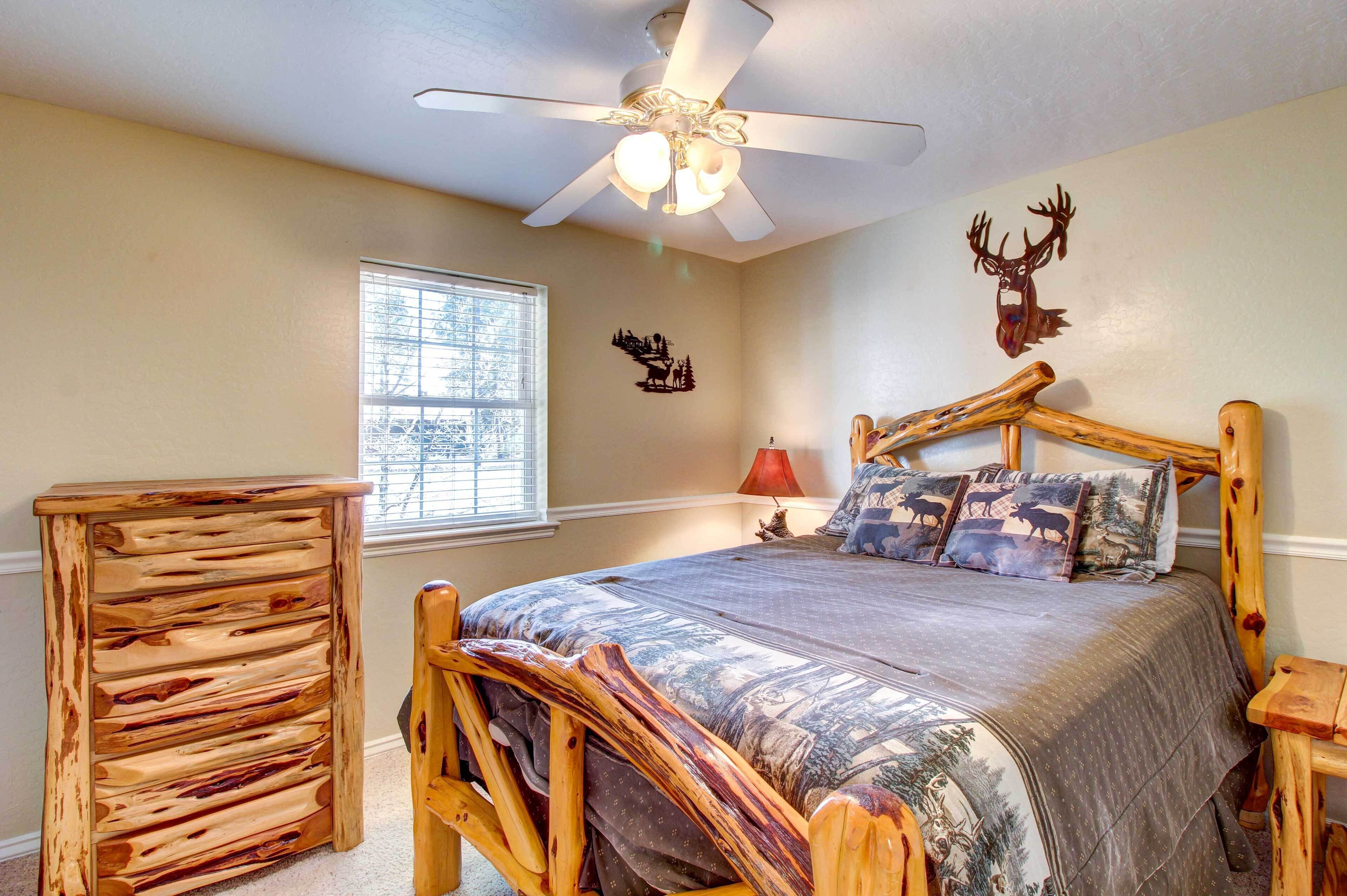 A bedroom with a bed, a wooden dresser, a ceiling fan, and a window.