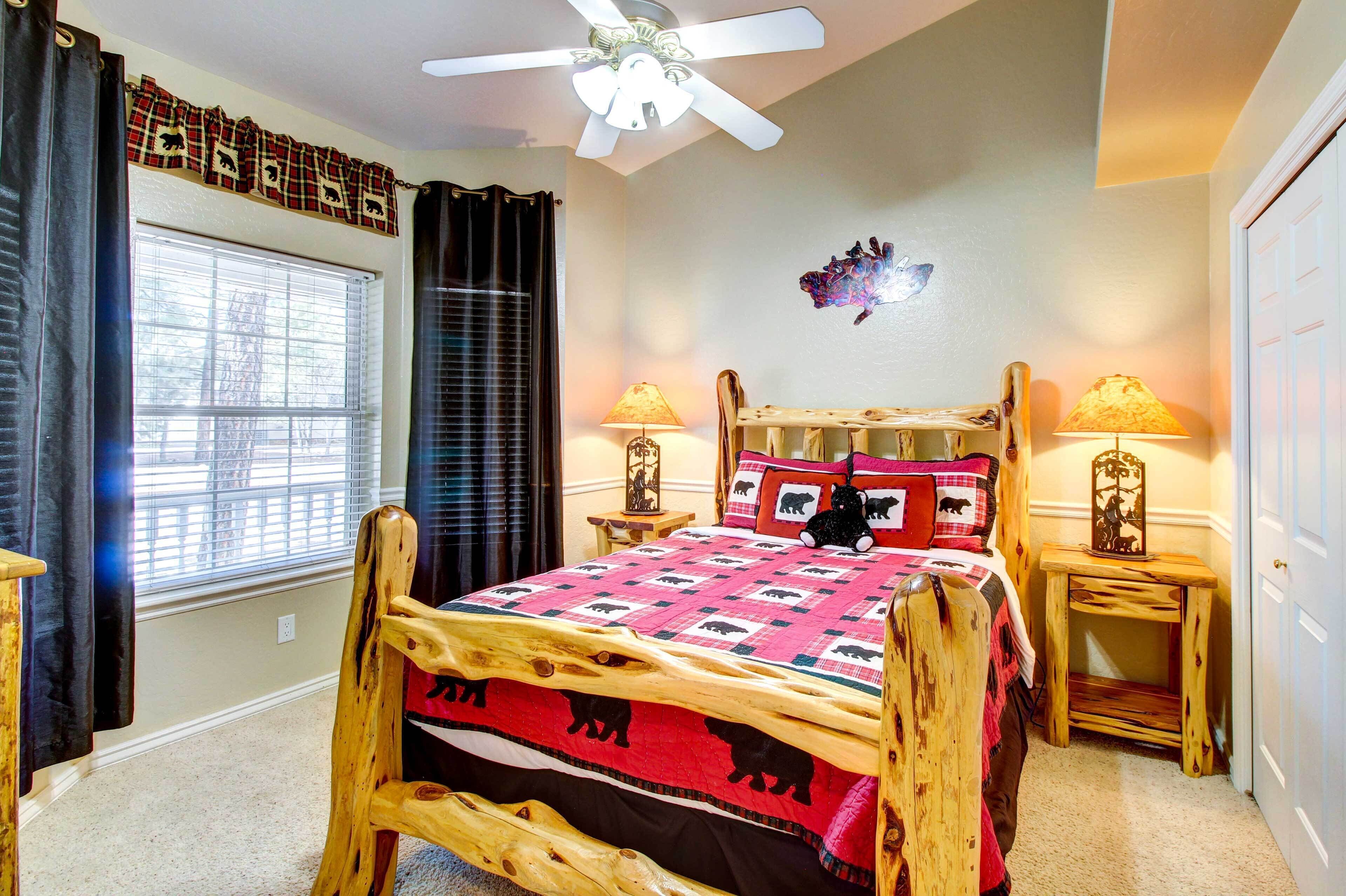 A bedroom with a wooden bed frame, a ceiling fan, two bedside lamps, a window with blinds, and a wall decoration.