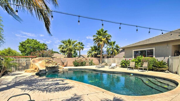 Un jardin avec une piscine, des palmiers et du mobilier d’extérieur.