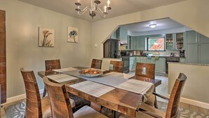 A dining area with a wooden table and chairs, a chandelier, and a view into the kitchen. - Spacious Tobyhanna Family Home: Pool/beach Access! (Tobyhanna)