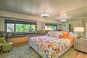 Ein Schlafzimmer mit einem großen Bett, einer Sitzbank mit Kissen, einem Sessel und einem Nachttisch mit Lampe.