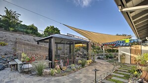 En terrasse med glasinddækning, stenkøer og flere krukker med planter.