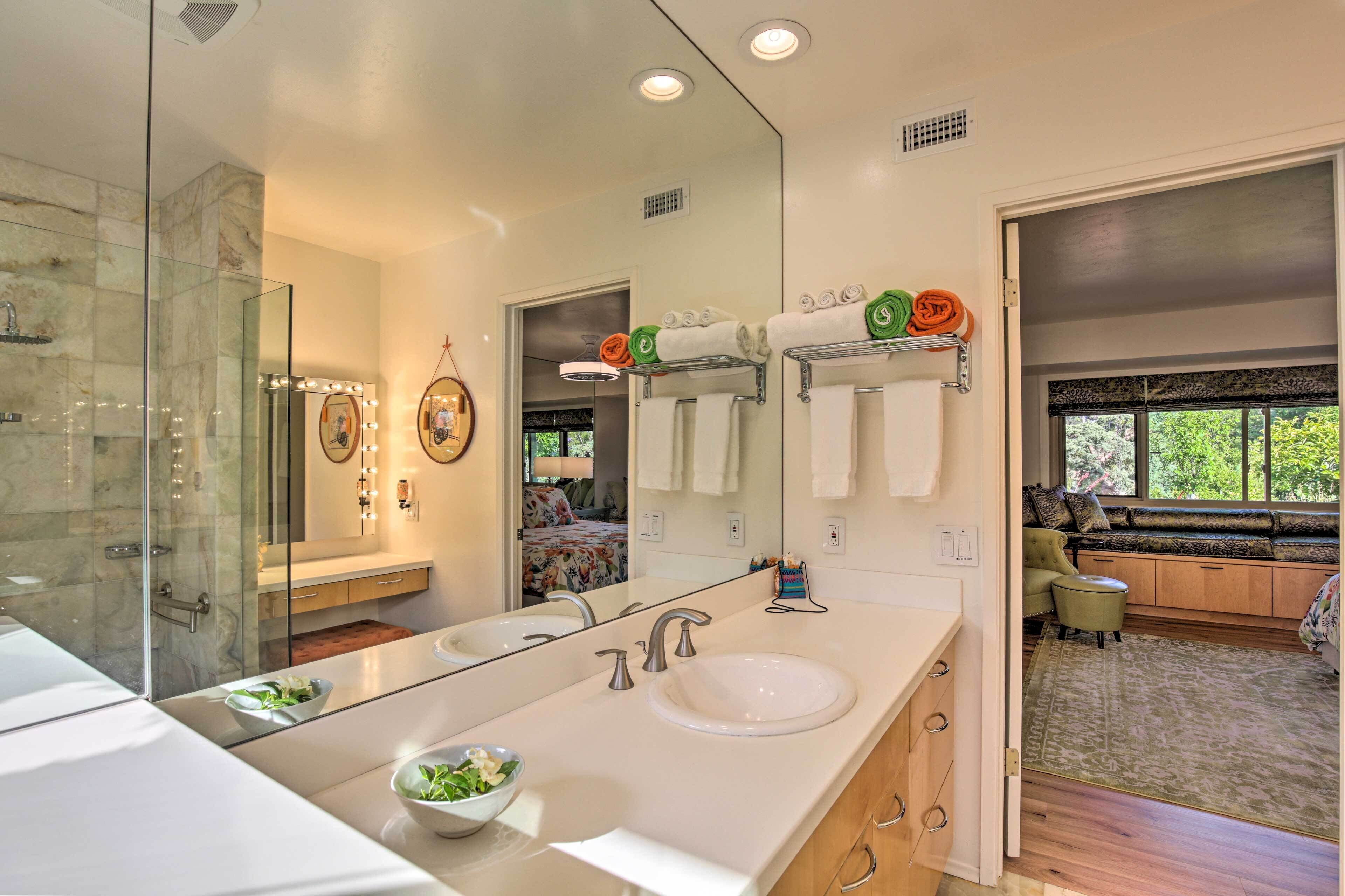 A modern bathroom with a large mirror, dual sinks, and a glass shower enclosure.