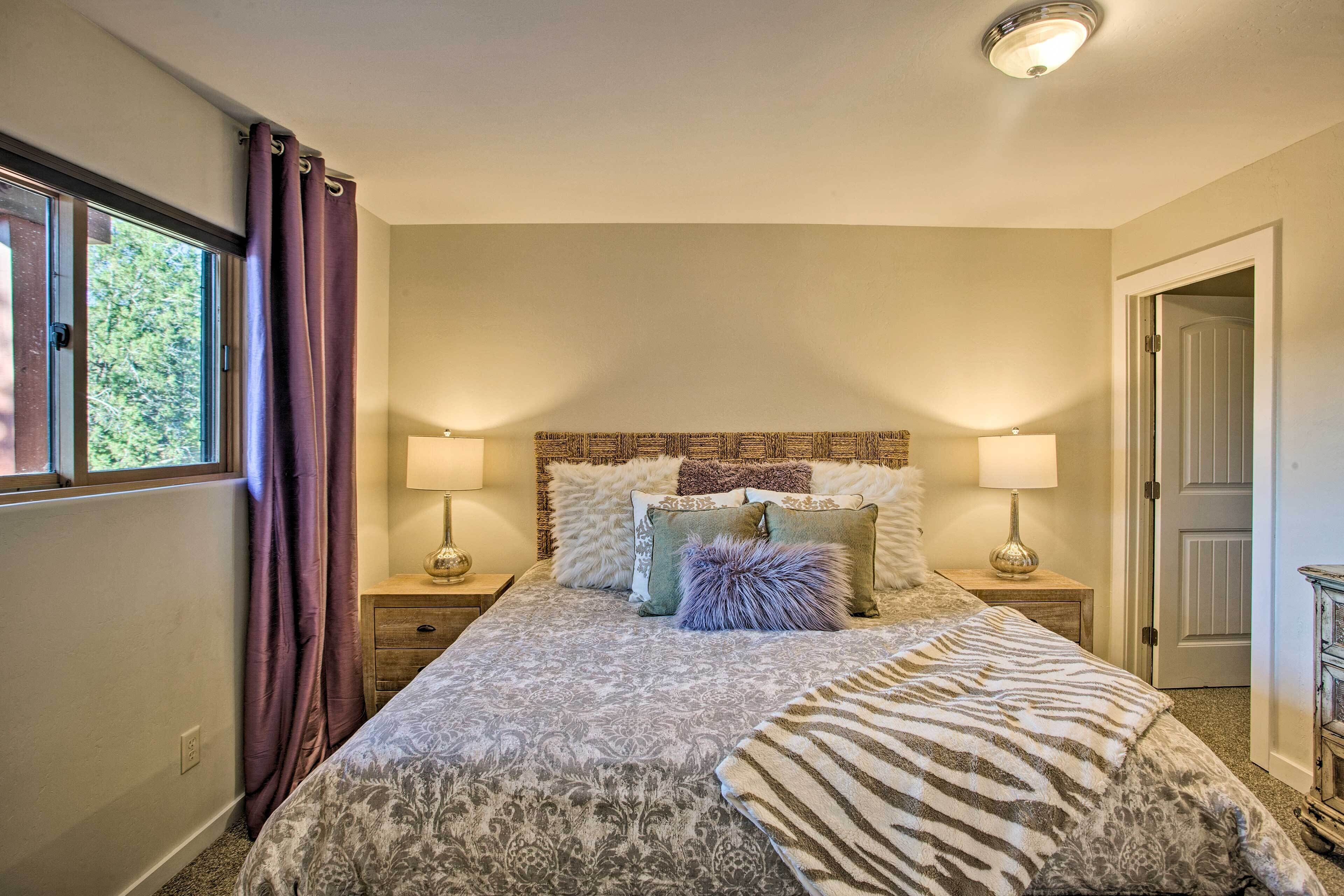 Een slaapkamer met een groot bed, twee nachtkastjes, een raam met gordijnen en een deur.