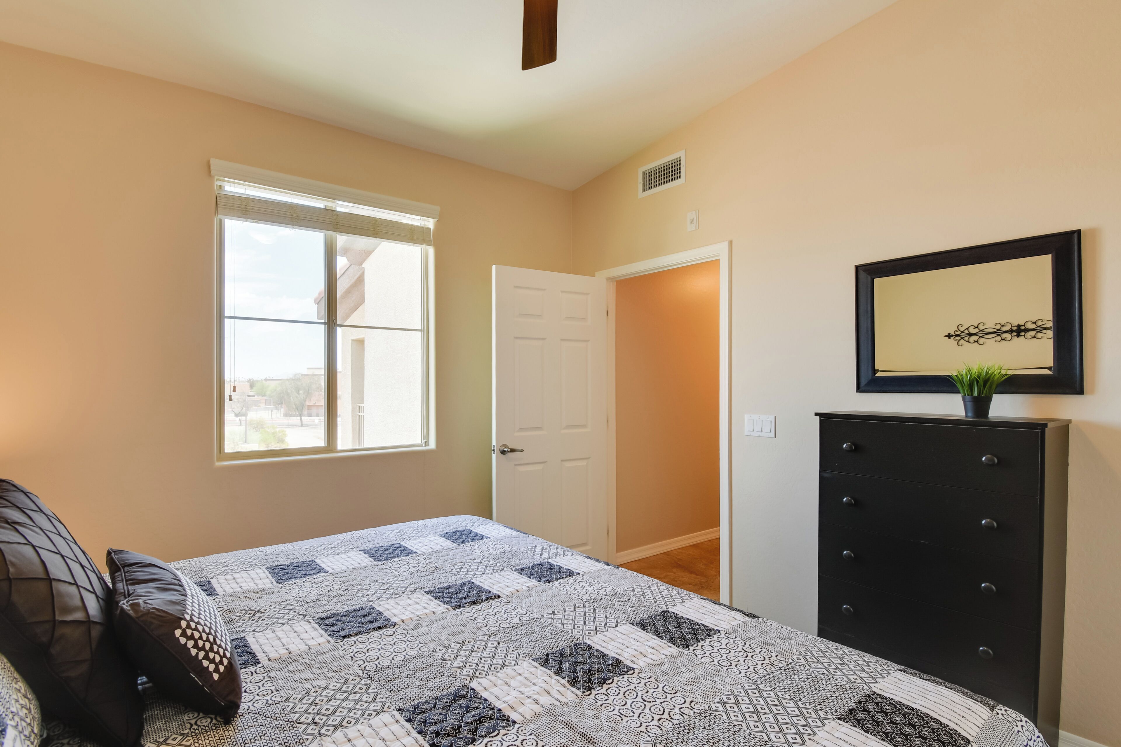 A bedroom with a bed, a dresser, a door, and a window.