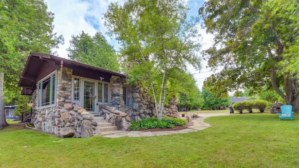 A stone house with a porch, surrounded by a well-maintained lawn and trees. - 1 Mi to Dtwn! Lakefront Earl Young Charlevoix Home (Charlevoix)