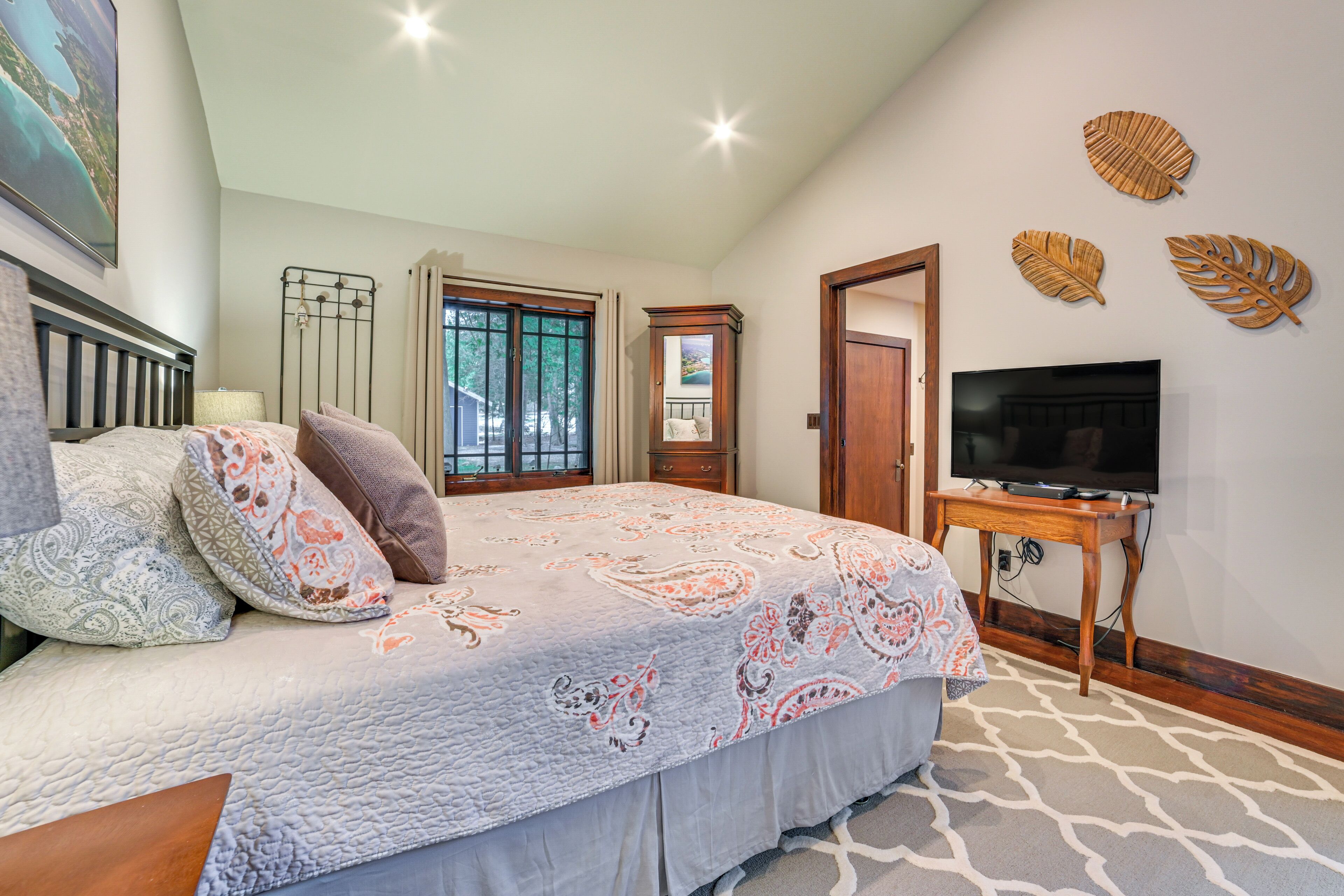 Quarto com cama, televisão, janela e decorações nas paredes.