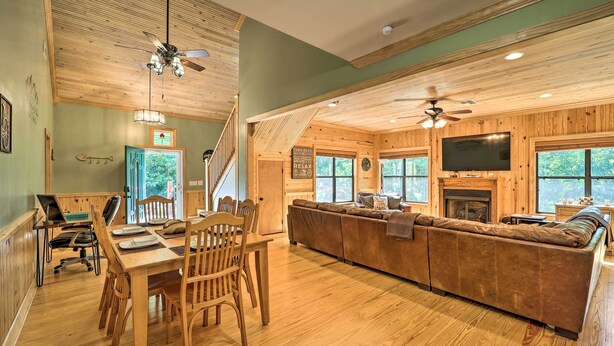 A spacious living area with a wooden floor, a sofa, a dining table with chairs, and a TV mounted on the wall. - 10 Mi to Grandfather Mountain: 'wolfe Creek Cabin' (Newland)