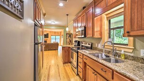 Una cocina con armarios de madera, electrodomésticos de acero inoxidable y encimera de granito.