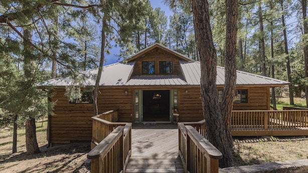 A wooden cabin with a front porch and a metal roof, surrounded by trees. - Well-appointed Alto Cabin w/ Fire Pit & Pool Table (Alto)