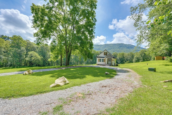A house with a gravel driveway, surrounded by lush green grass and trees. - Modern Appalachian Vacation Rental w/ River Access (Pennington Gap)