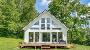A white house with a wooden deck, large windows, and a grassy yard. - Modern Appalachian Vacation Rental w/ River Access (Pennington Gap)