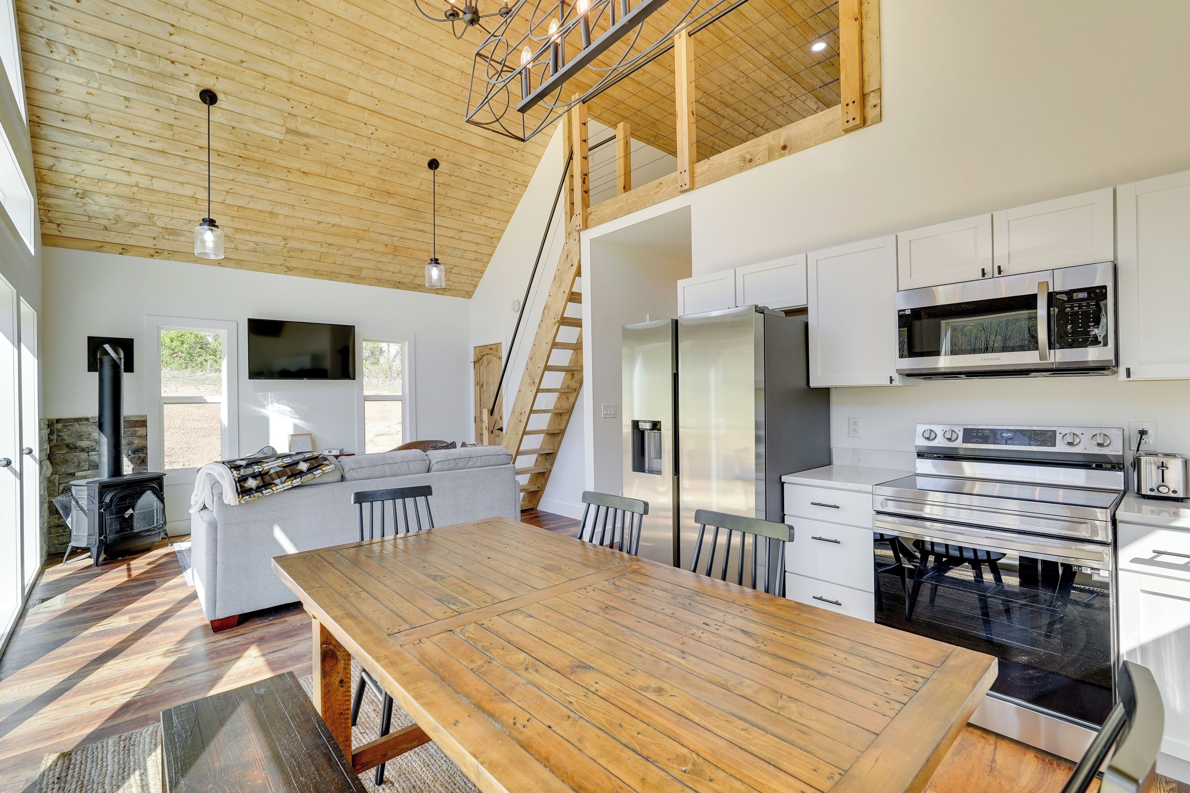 A modern kitchen with white cabinets, stainless steel appliances, and a wooden dining table.