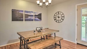 Ein Essbereich mit Holztisch und Bank, einer Chandelier und zwei gerahmten Landschaftsbildern an der Wand.