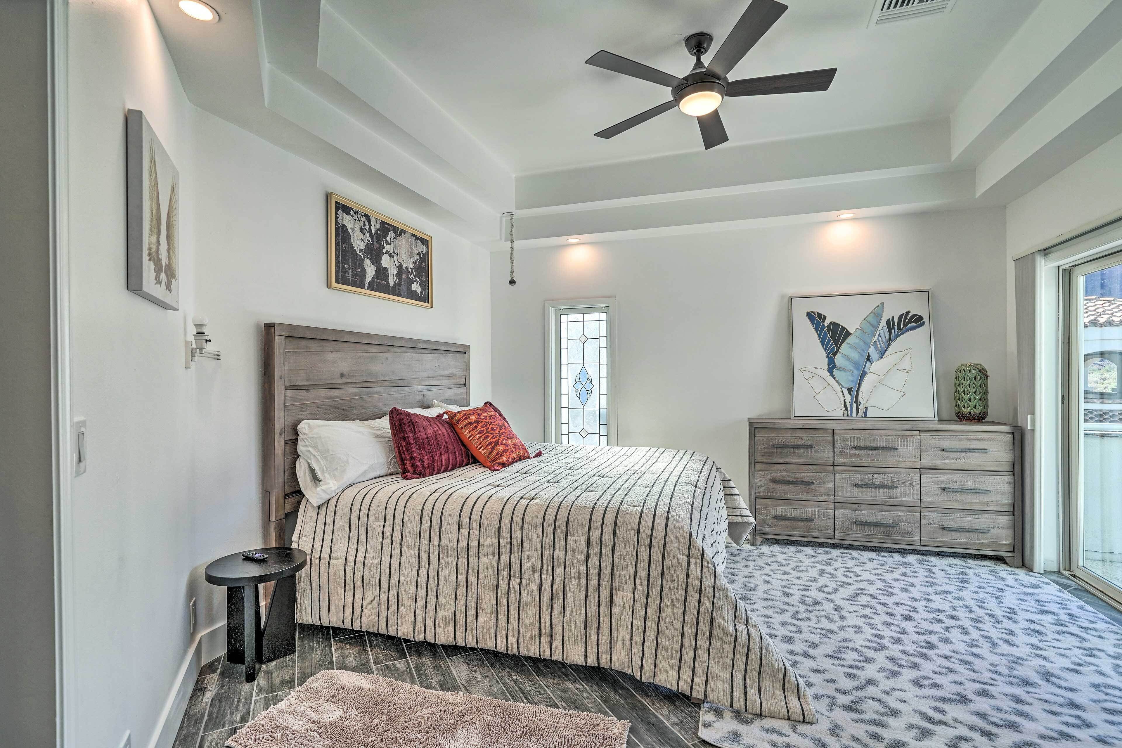 A bedroom with a bed, a dresser, a ceiling fan, and a window.