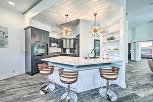Una cocina moderna con una isla central, armarios oscuros y tres taburetes de bar.