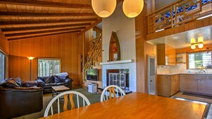 Ein Holzinterieur mit Essbereich, Sofa, Fernseher, Kamin, Küche und einer Treppe.