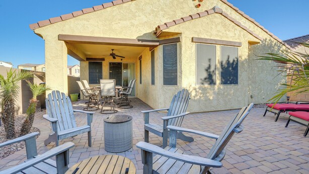 Une maison dotée d’un patio comprenant des fauteuils Adirondack, une table et un ventilateur de plafond.