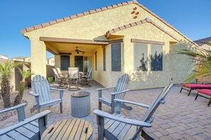 Una casa con patio, con poltrone Adirondack, un tavolo e una ventola a soffitto.