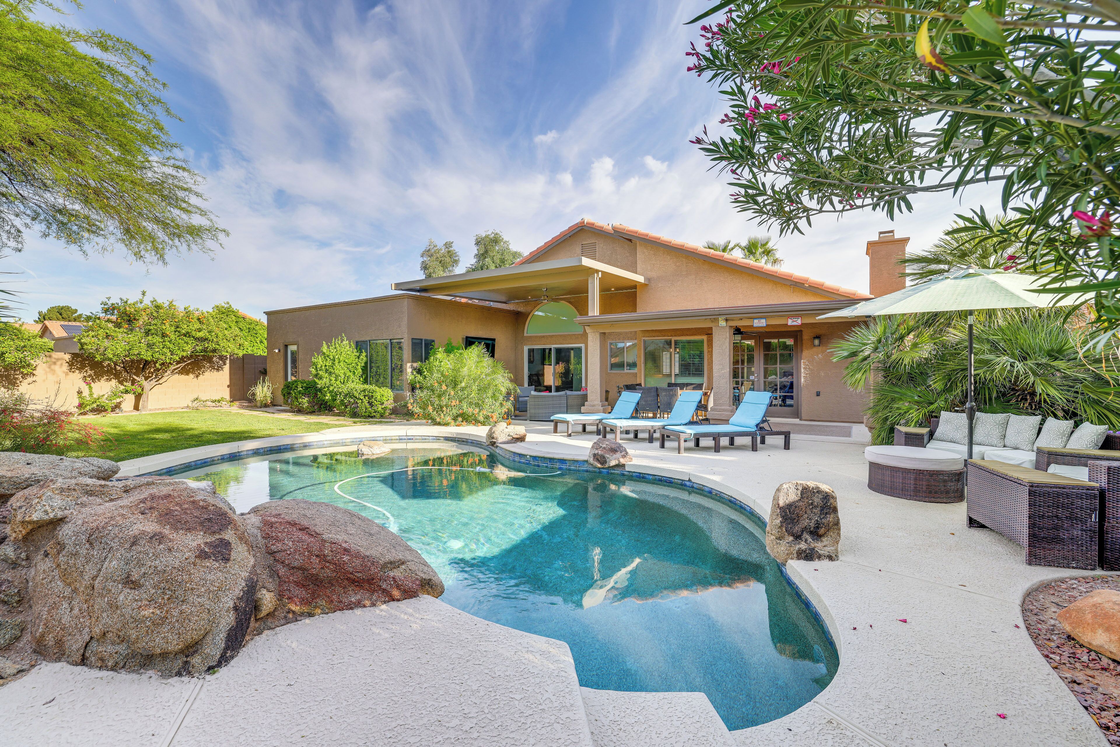 A modern house with a swimming pool, outdoor seating, and a well-maintained garden.