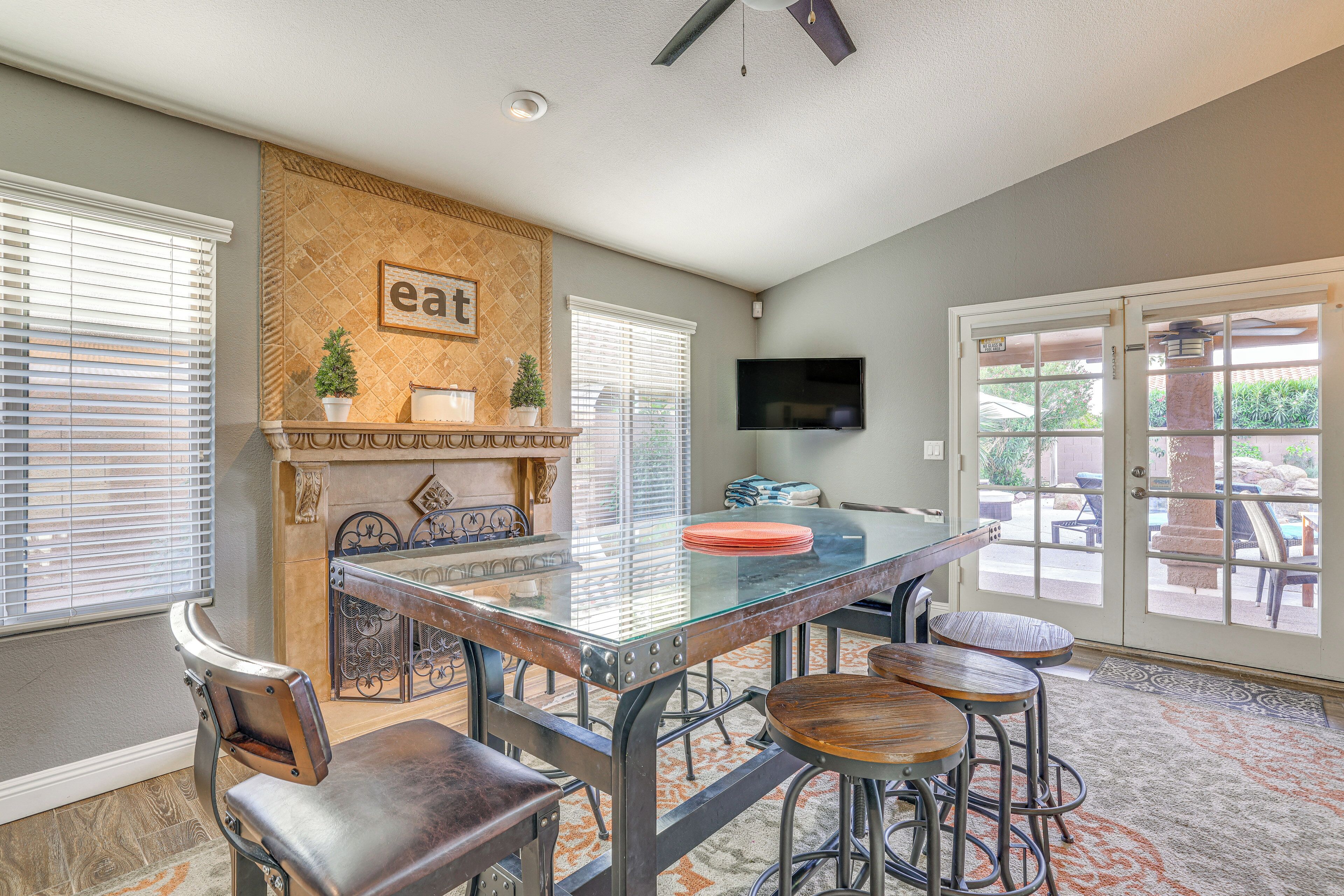 A dining area with a glass-top table, metal chairs, and a fireplace.