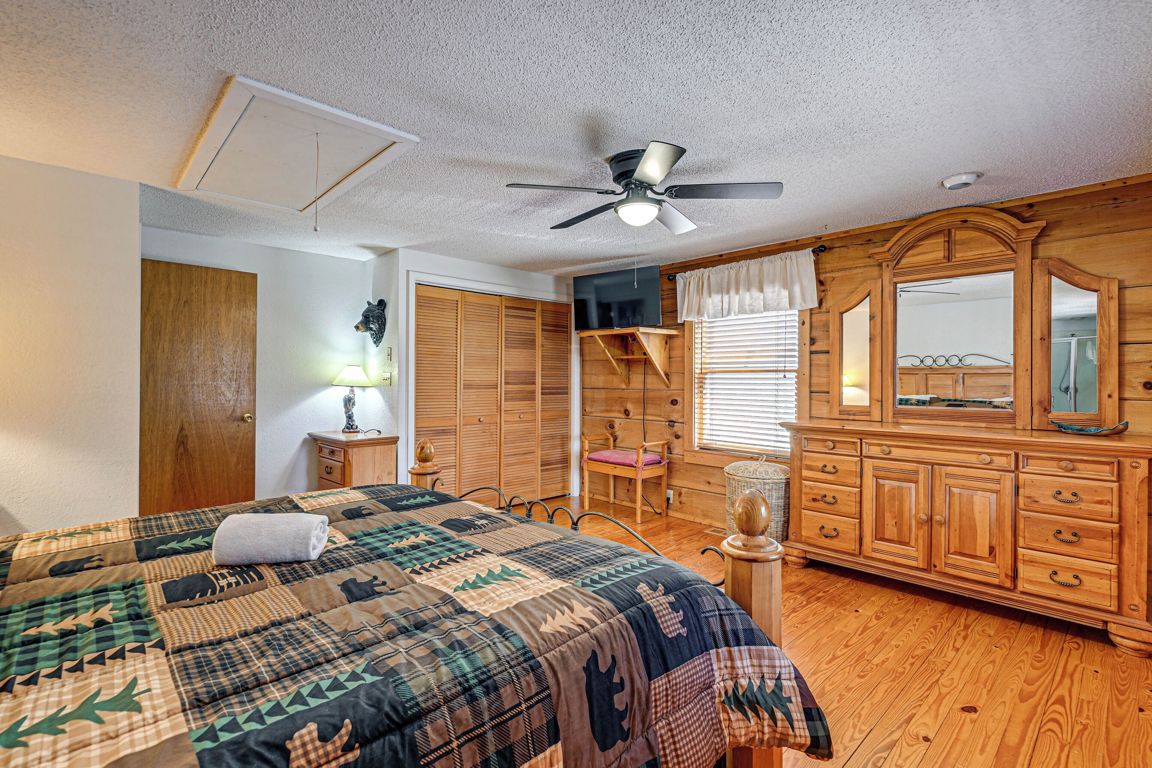 A bedroom with a bed, wooden wardrobe, and a ceiling fan.