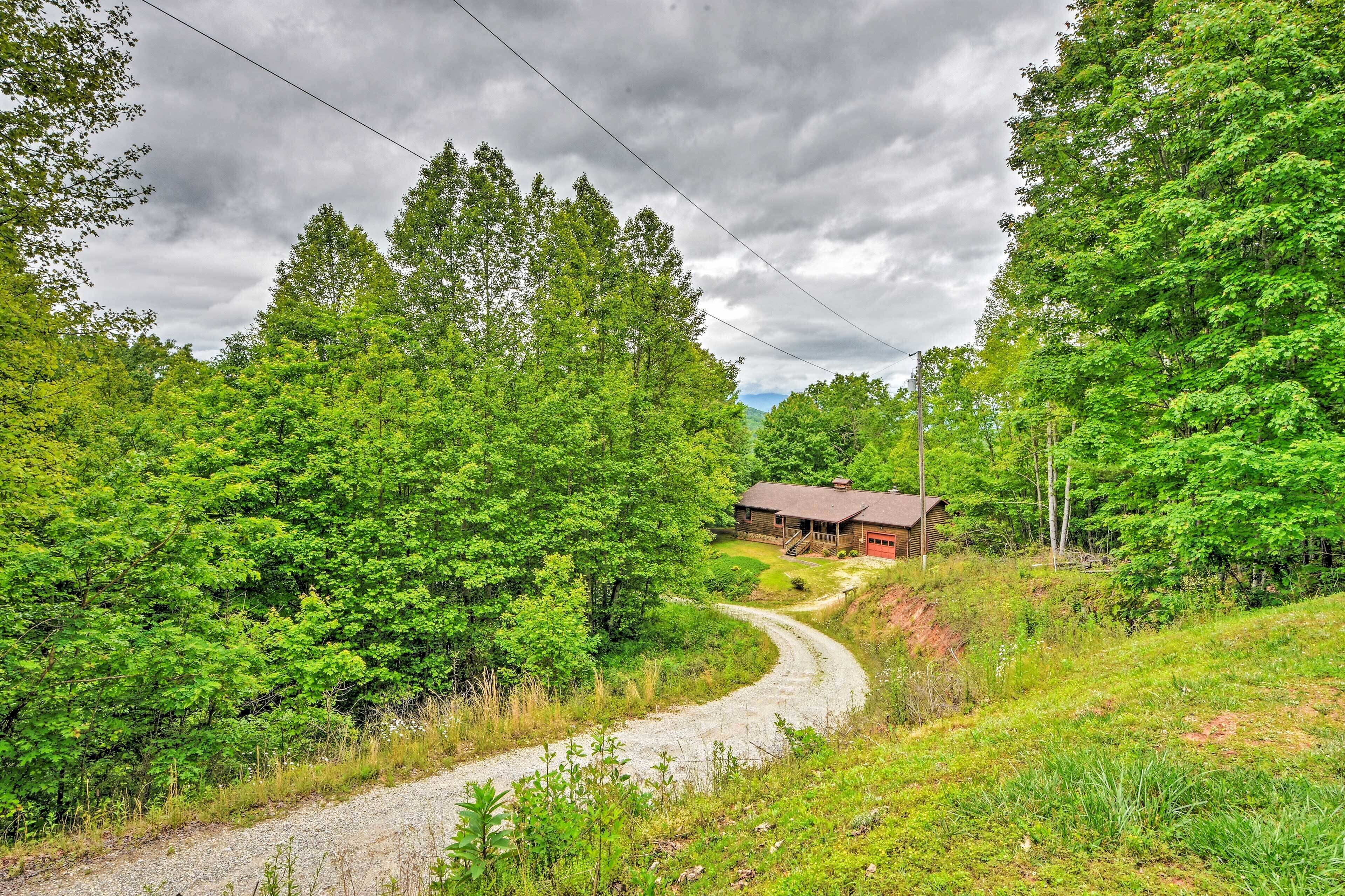 A rural road curving through a forested area with a small building on the right.