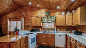 A wooden cabin-style kitchen with wooden cabinets, a microwave, stove, sink, and a dishwasher. - Bryson City Cabin w/ Hot Tub, Views & Pool Table! (Bryson City)