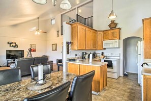 A modern kitchen with wooden cabinets, a central island, and a dining area with a marble table and leather chairs. - Lake View Home w/ Grill: Hike, Boat, Relax! (Kelseyville)