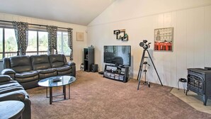 Una sala de estar con un sofá de cuero, una mesa de centro de vidrio, un televisor, una chimenea y un trípode.