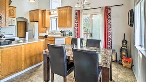 Una cocina con armarios de madera, encimera de mármol y una mesa de comedor con sillas.