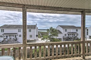 Une terrasse en bois offrant une vue sur des maisons blanches et une zone verdoyante.