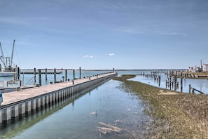 A pier extending into calm water with a docked boat on the left and a building on the right. - Chincoteague Townhome w/ Pony Views From Deck! (Chincoteague)
