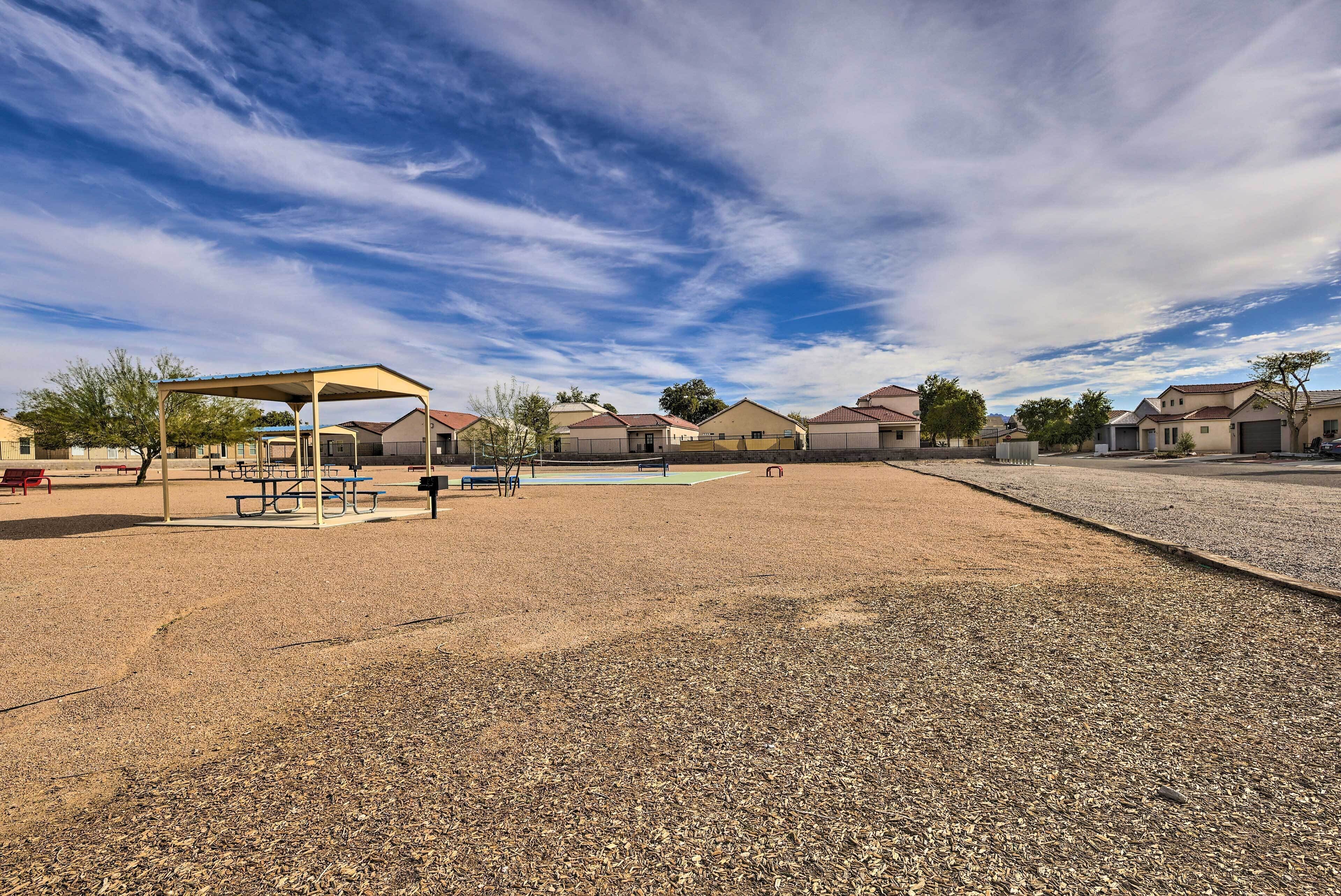 A playground with picnic tables and a covered area, surrounded by houses.